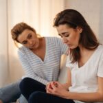 Kaksi naista sohvalla, toinen kuuntelee myötätuntoisesti toista