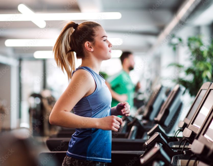 Nainen kuntosalilla juokesemassa juoksumatolla